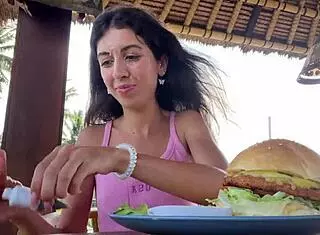 cute girl enjoys burger in public cafe