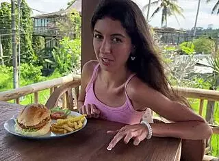 cute girl enjoys burger in public cafe