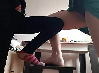 Middle aged woman sits in skirt while student in jeans masturbates nearby