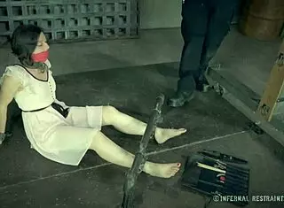 Petite brunette bound in metal bondage for whipping and fingering.