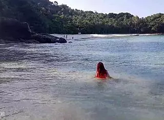 Naked redhead bathes on public beach.