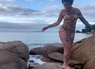 Bold shibari bondage exposes small tits in public outdoor setting