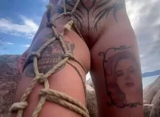 Bold shibari bondage exposes small tits in public outdoor setting