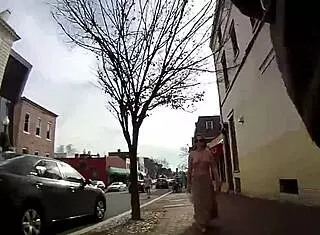 Girlfriend walks topless around town with friend in public outdoor setting.