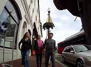 Girlfriend walks topless around town with friend in public outdoor setting.