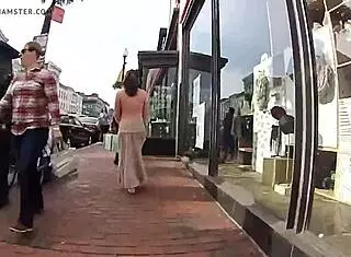 Girlfriend walks topless around town with friend in public outdoor setting.